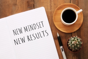 top view image of table with open notebook and the text new mindset new results. success and personal development concept