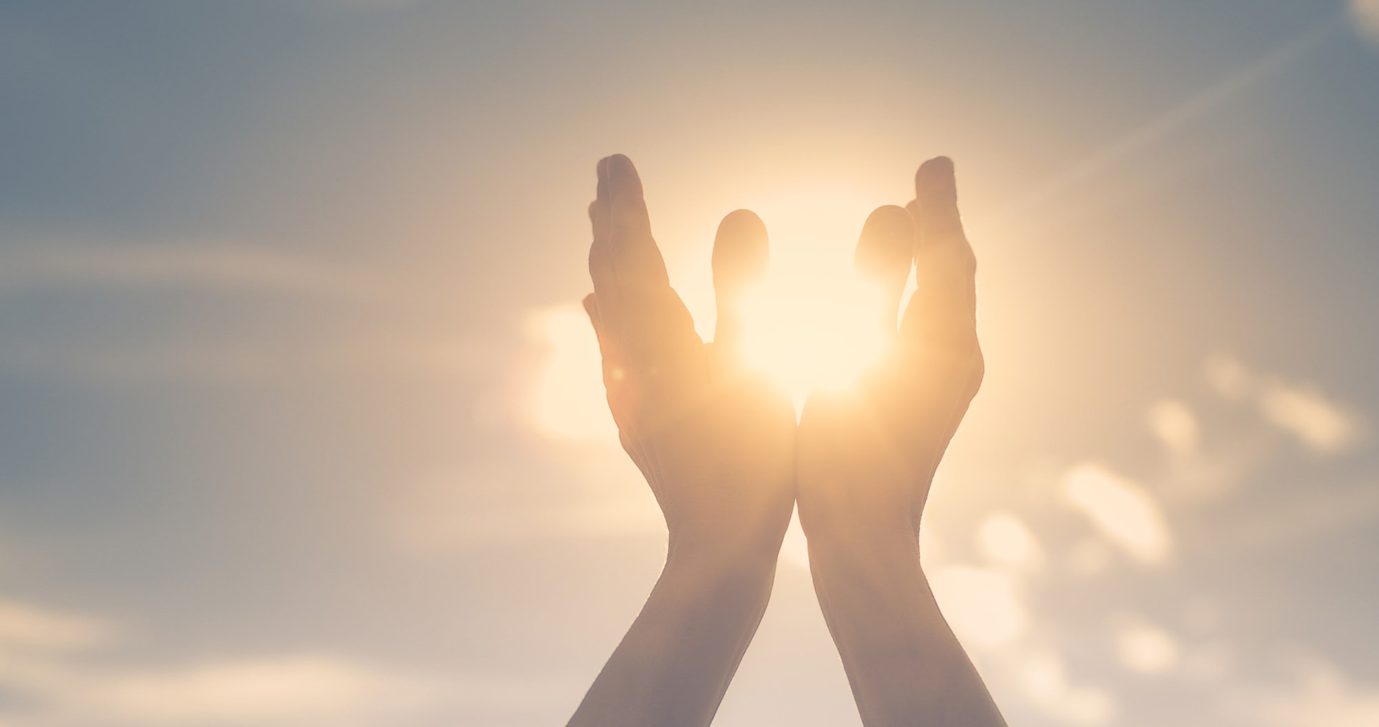 hands in the sky holding the sun. Spiritual healing concept.